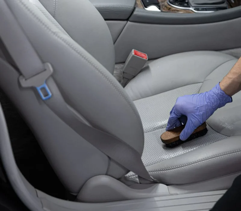 Car detailing studio worker cleaning car leather seat